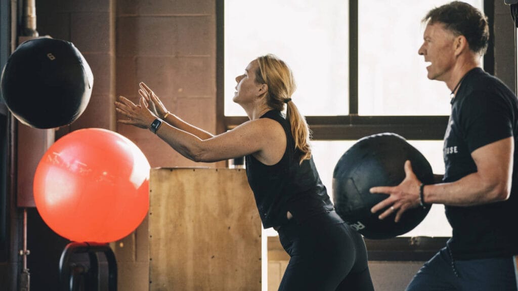 Man and woman training with wall ball